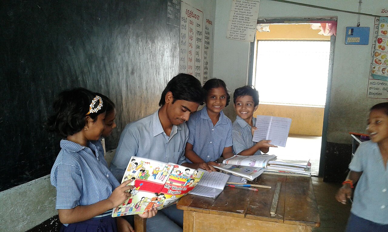Girls reading books together with their teacher