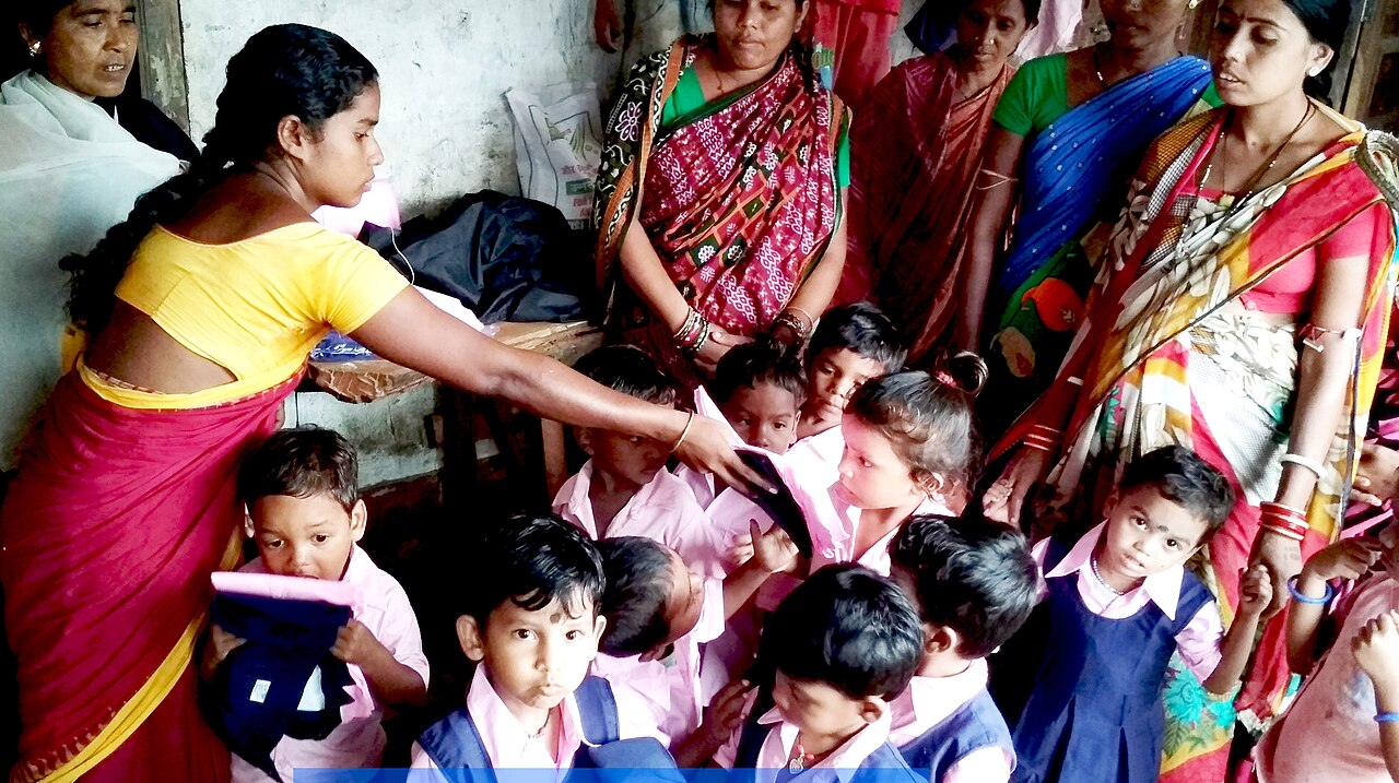 Anganwadi worker distributing new clothes to young children
