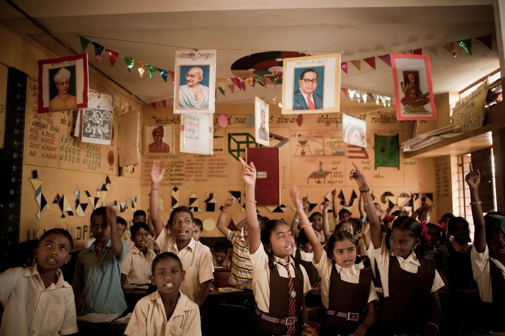 Schoolchildren in uniform cheering together in their school hall